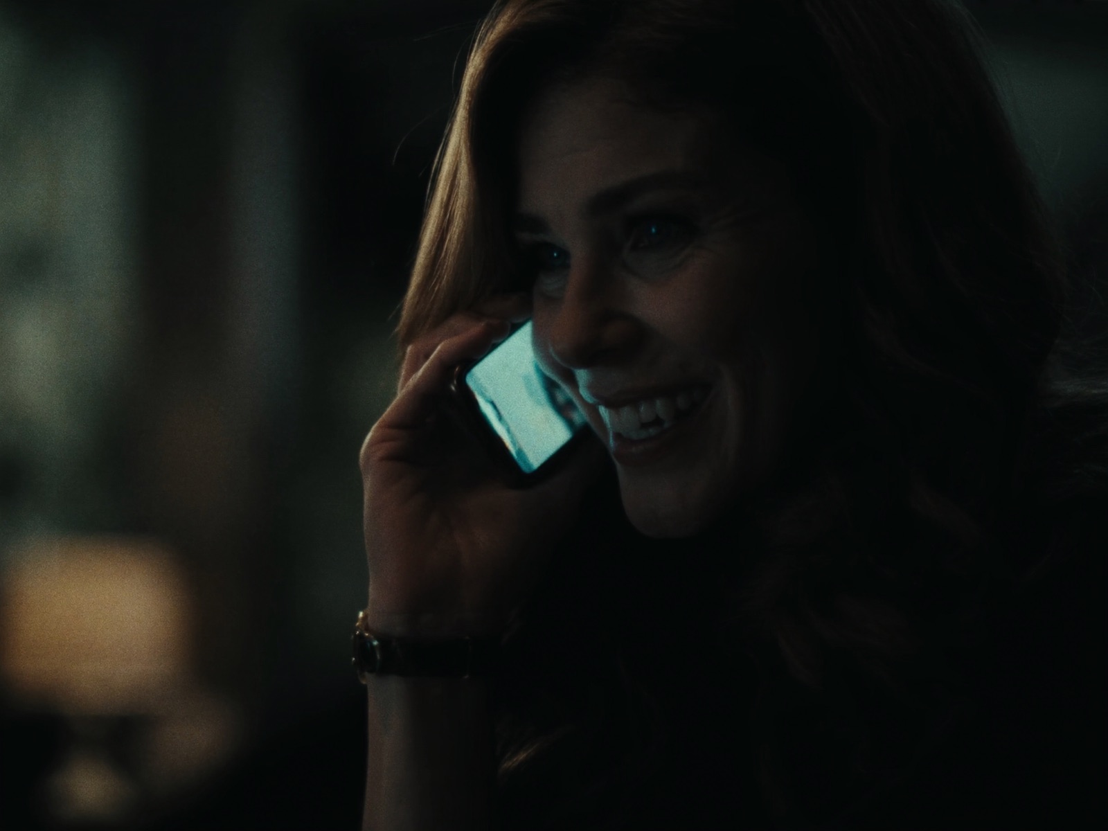 A woman smiles on the phone in her living room in the evening as her dinner reservation is confirmed.