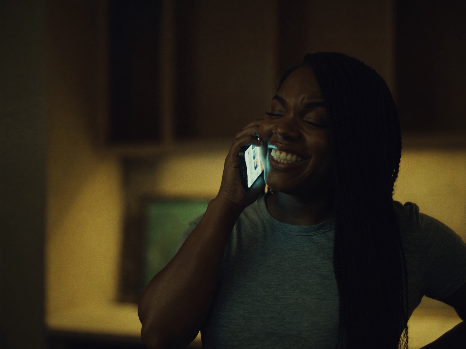 A homeowner in her half-renovated kitchen smiles with relief while talking on the phone in the evening.
