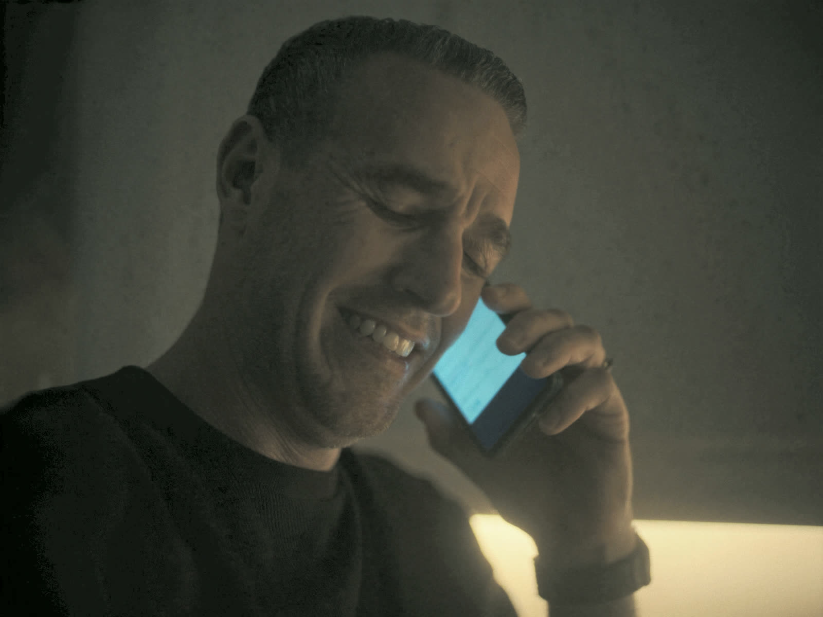 A man in his kitchen smiles with relief as his appointment gets booked over the phone.