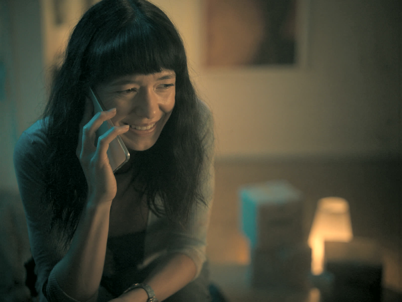A tenant in her apartment smiles with relief on the phone as her request gets logged.